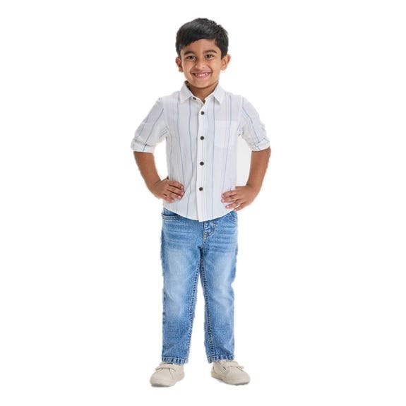 A young child is wearing a white button-up shirt with thin vertical stripes, paired with light blue jeans and beige shoes.