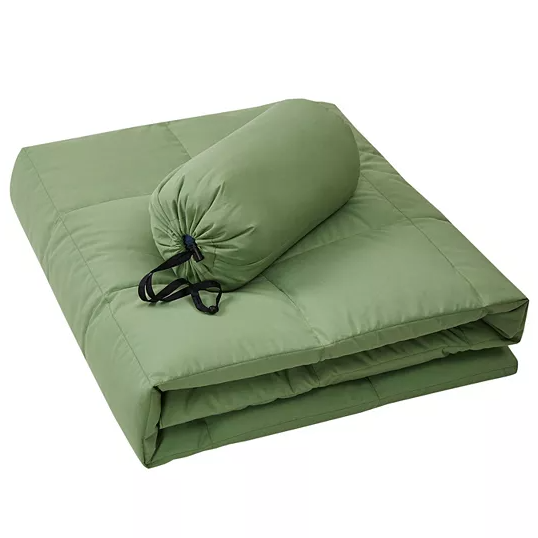 Green packable down throw with quilted design, shown folded alongside its compact storage bag. Ideal for convenience and portability.