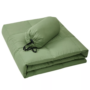 Green packable down throw with quilted design, shown folded alongside its compact storage bag. Ideal for convenience and portability.