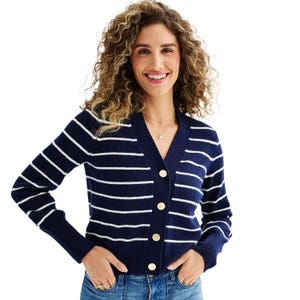 Blue and white striped cardigan with gold buttons, featuring a V-neck and ribbed cuffs. Worn over jeans, it offers a casual yet polished look.