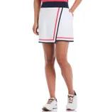 A woman wearing a sporty white skort with navy and pink trim, paired with white sneakers.