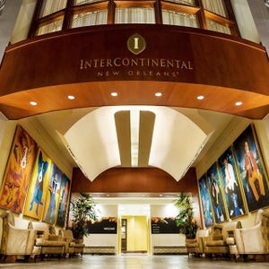 Lobby of InterContinental New Orleans hotel with an overhead sign and artistic wall paintings.