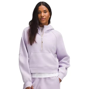 A woman wears a pale purple hoodie with a half-zip closure and matching pants.