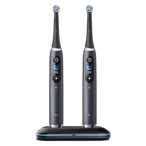 Two electric toothbrushes with round brush heads are standing on a charging base.