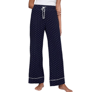 Navy blue polka dot pajama pants with a white drawstring waistband and subtle piping at the cuffs, worn by a person with bare feet.