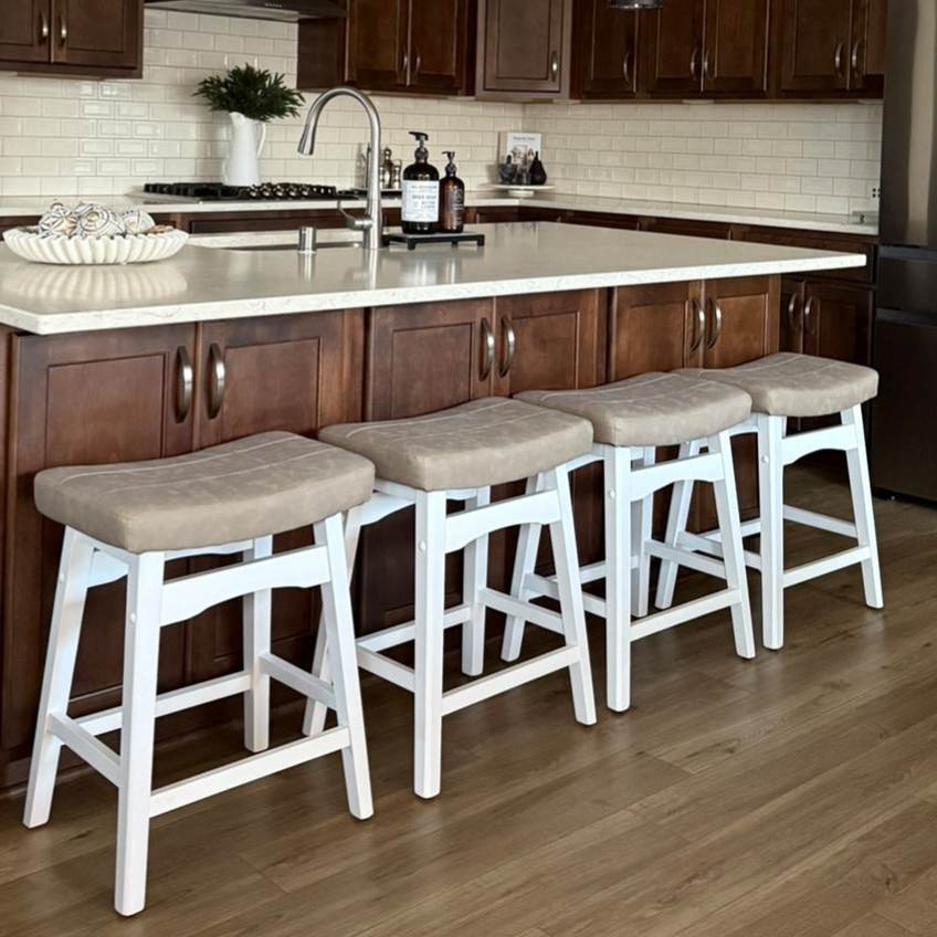 A kitchen island with a white countertop and four cushioned stools. The setting features dark wood cabinets, a stainless steel faucet, and neutral subway tile backsplash.