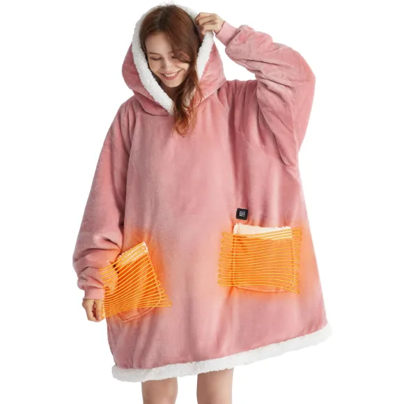 A pink, oversized hoodie with a white sherpa lining and integrated heated pockets. The cozy garment features orange heating elements visible on the front, designed for warmth and comfort.