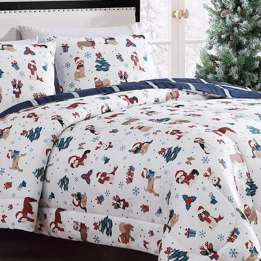 Festive bedding set with a holiday theme, featuring illustrations of dogs, Christmas trees, gifts, and snowflakes in red, blue, and brown on white fabric, complemented by navy striped sheets.