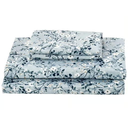 A set of pale blue floral bed sheets, including a flat sheet, fitted sheet, and pillowcase with a delicate white and dark blue flower pattern.