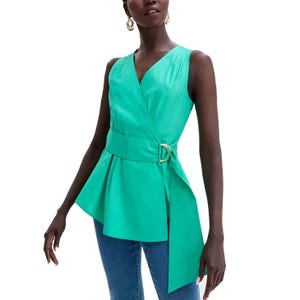 A sleeveless wrap-style blouse in turquoise with a V-neckline, featuring a wide belt with a gold buckle and an asymmetrical hem. Paired with blue jeans.