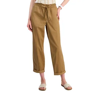 Tan drawstring pants with front patch pockets, cuffed hems, and a relaxed fit, paired with white textured slide sandals.
