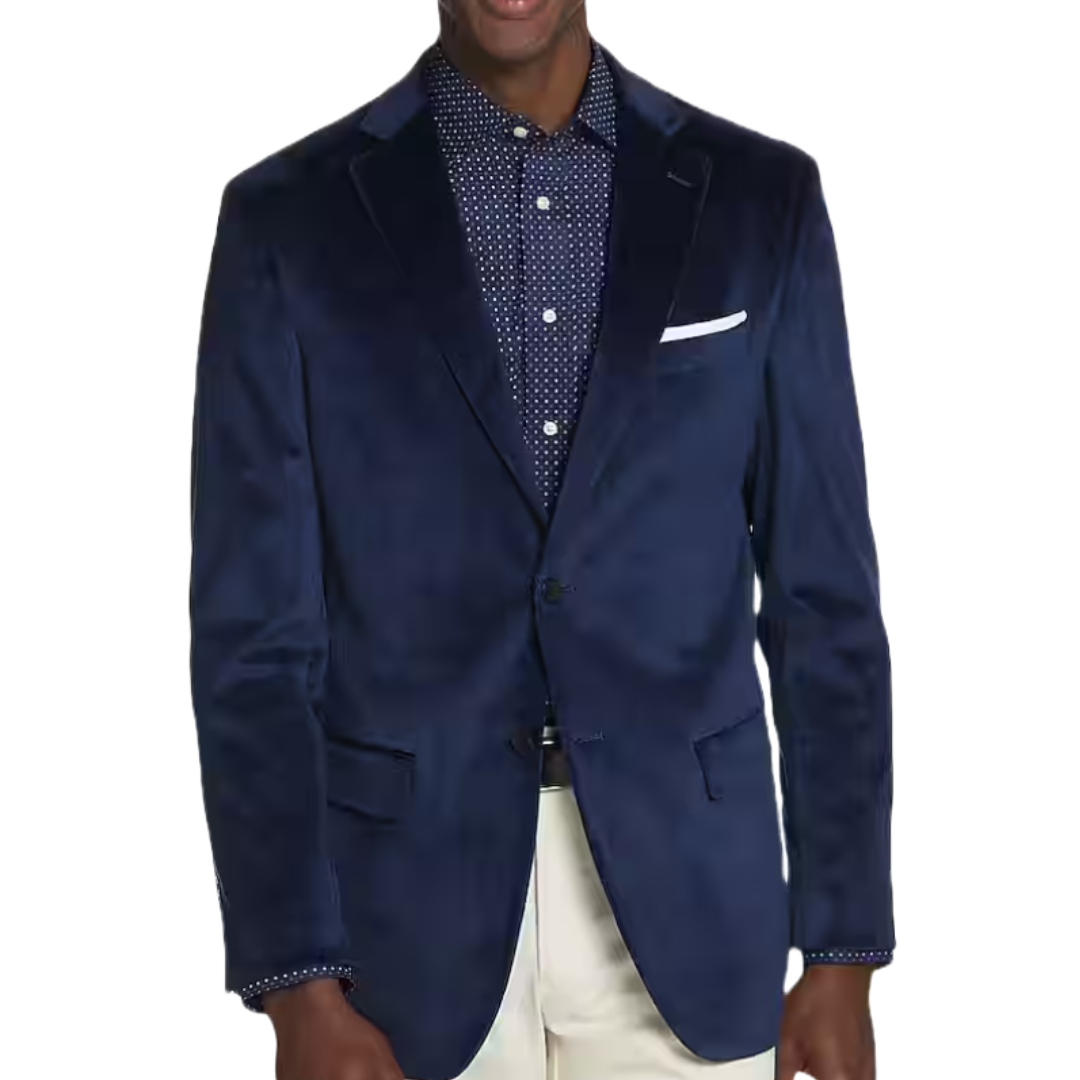 A man is wearing a navy blue blazer over a polka-dot shirt, paired with light-colored pants.