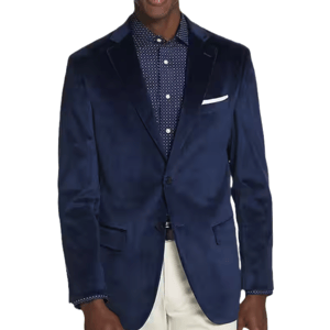 A man is wearing a navy blue blazer over a polka-dot shirt, paired with light-colored pants.