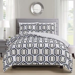A bed with a geometric-patterned comforter set including pillows, in a room with a round mirror on the wall.