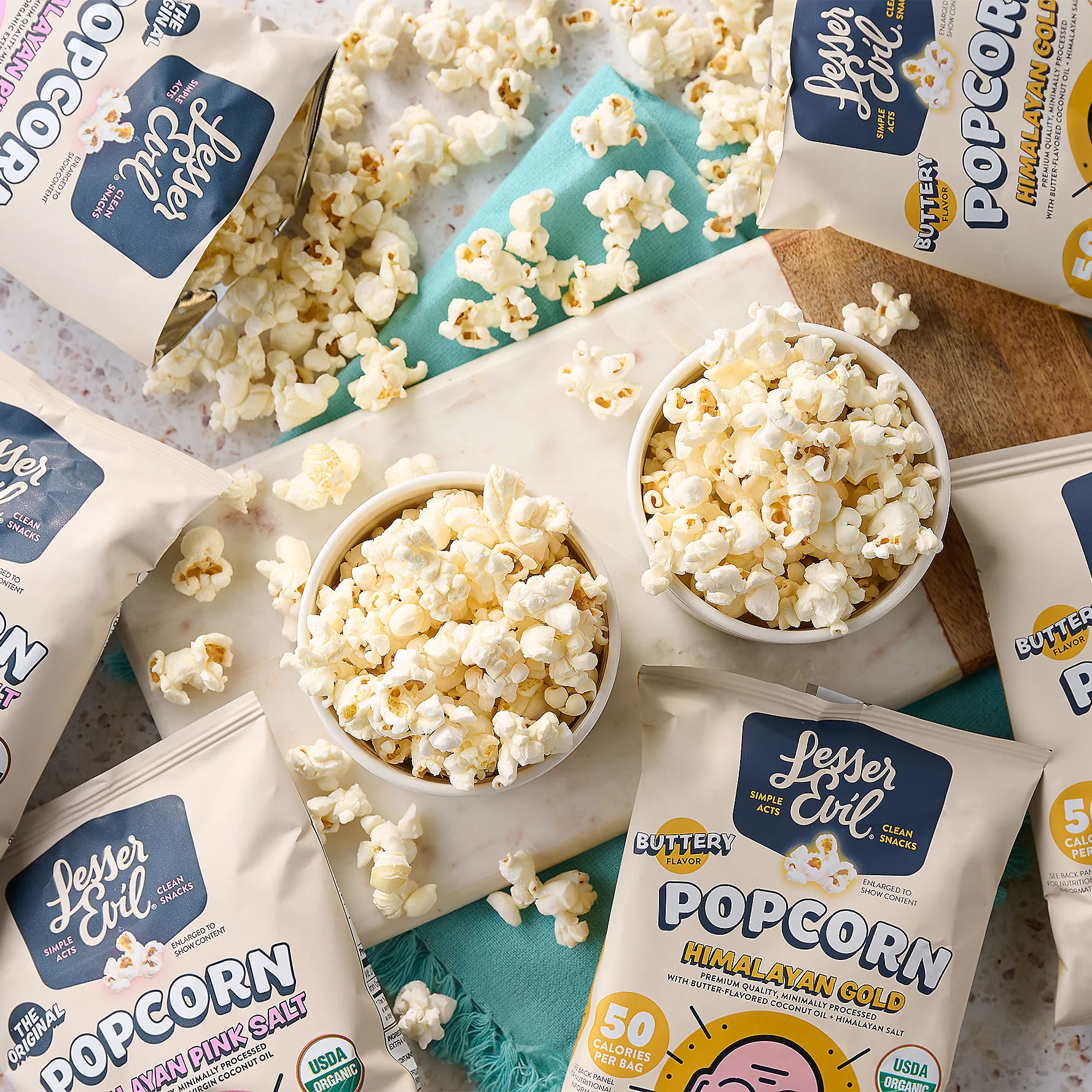 32ct Lesser Evil Popcorn Snack Bags feature Himalayan Pink Salt and Buttery flavors. USDA organic, labeled as clean snacks with 50 calories per serving, and packaged in beige bags with brand logo and flavor details.