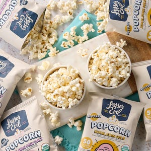 32ct Lesser Evil Popcorn Snack Bags feature Himalayan Pink Salt and Buttery flavors. USDA organic, labeled as clean snacks with 50 calories per serving, and packaged in beige bags with brand logo and flavor details.