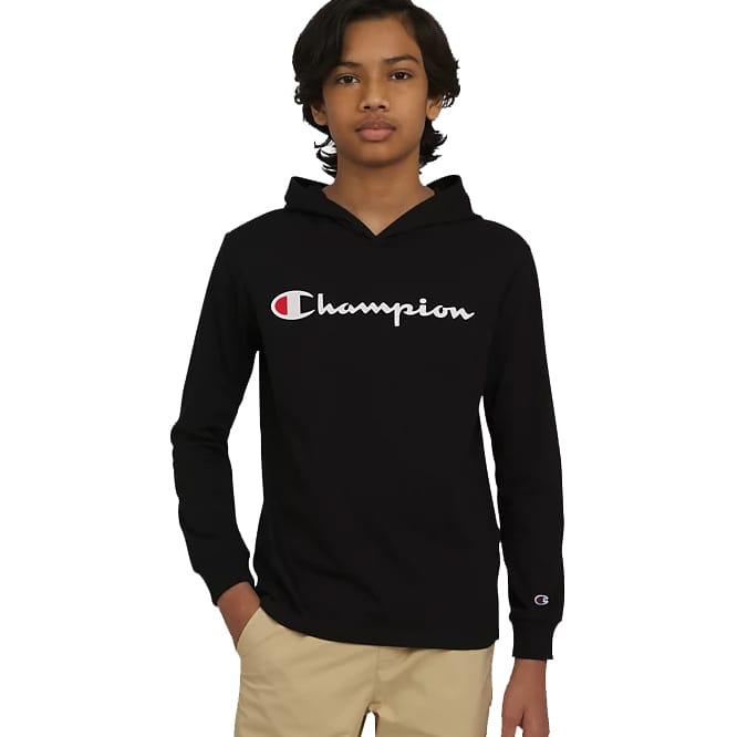 A young person wearing a black Champion hoodie with the brand's logo on the front and beige pants.