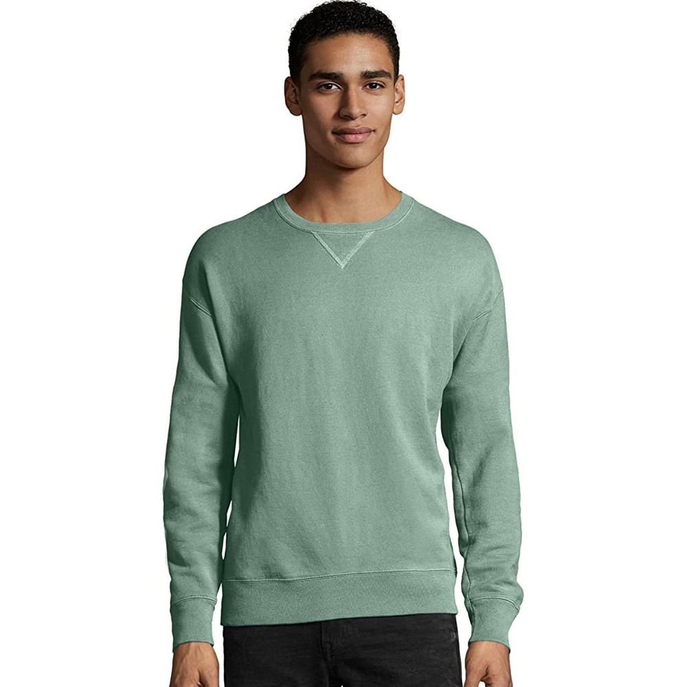 A man wearing a light green Hanes fleece sweatshirt with a crew neck and ribbed cuffs. The sweatshirt has a relaxed fit and a V-shaped stitch detail at the neckline.