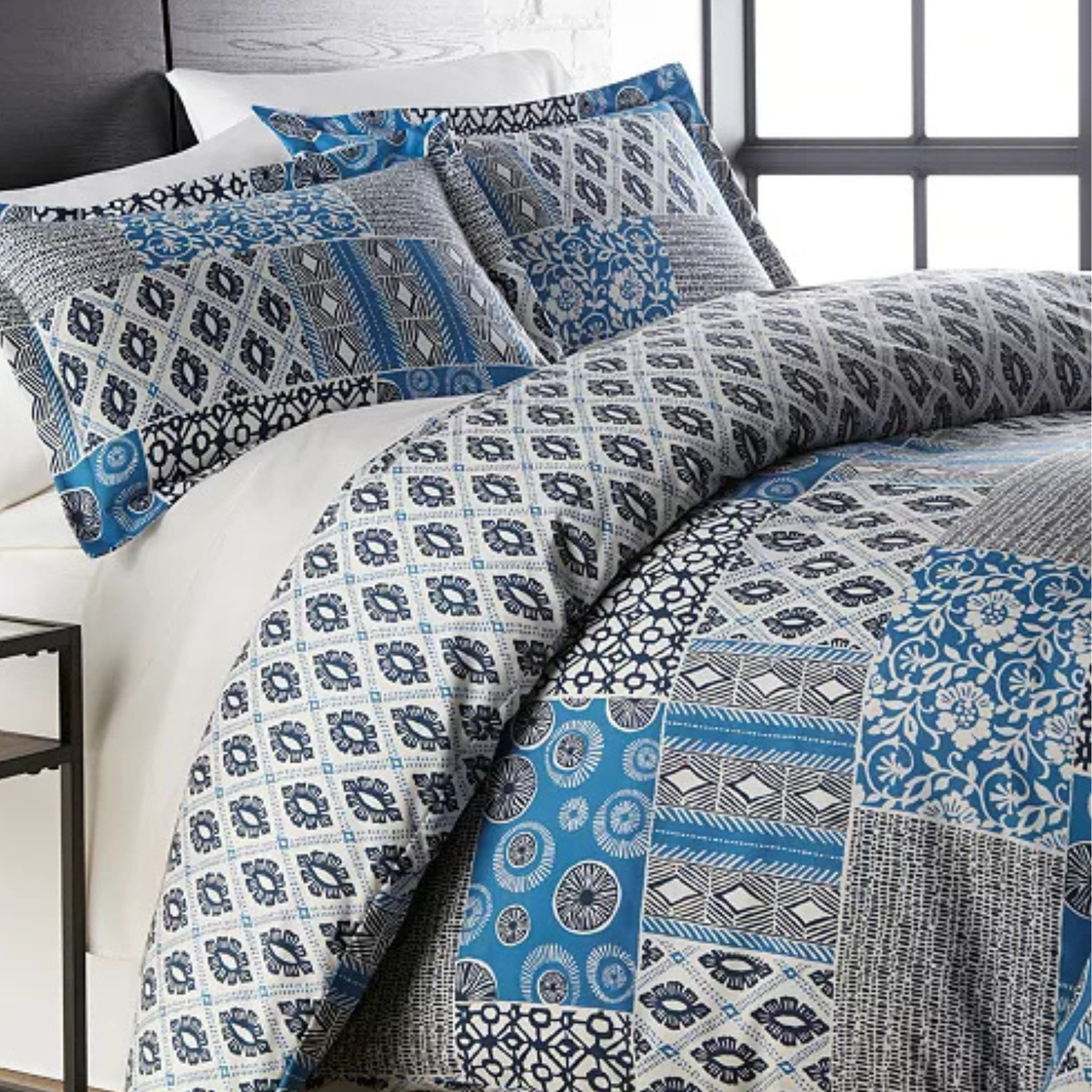 A queen-sized comforter set with a patchwork design featuring a mix of blue and gray patterns on the pillows and comforter.