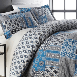 A queen-sized comforter set with a patchwork design featuring a mix of blue and gray patterns on the pillows and comforter.