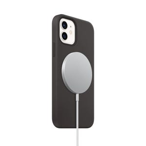 A silver MagSafe wireless charger is attached to the back of a black phone case. The charger features a circular pad and a connected cable for charging compatible devices.