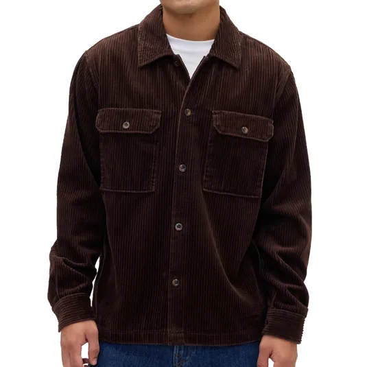 Dark brown corduroy button-up shirt with front pockets and collar, worn over a white shirt, paired with blue jeans.