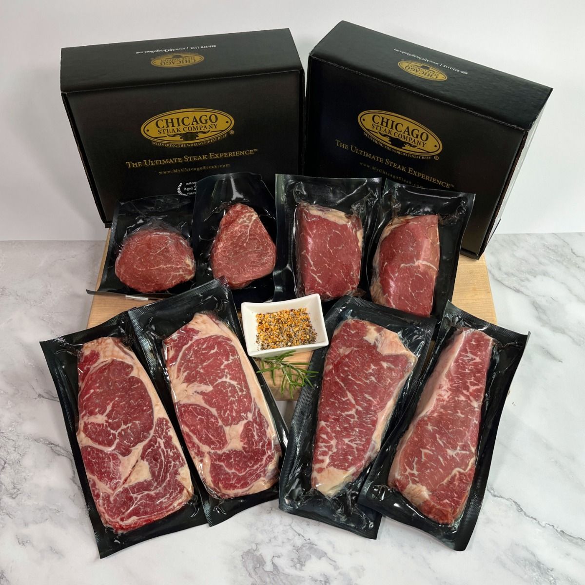 Chicago Steak Company offers a variety of vacuum-sealed steak cuts displayed alongside their branded boxes, featuring premium meat selections like ribeye and filet mignon, with a small dish of seasoning included.