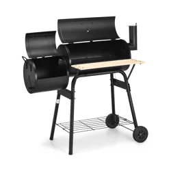 A black outdoor charcoal grill with an offset smoker, featuring a main cooking chamber, wooden shelf, lower storage rack, and sturdy wheeled legs for mobility.