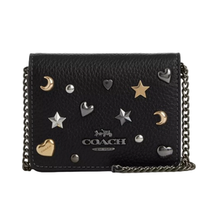 A black Coach wallet with a chain strap, featuring metallic star, heart, and moon embellishments in various colors.
