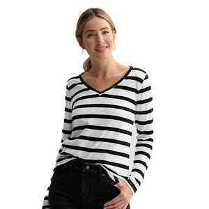 A woman is wearing a long-sleeve, black-and-white striped V-neck shirt paired with black pants.