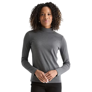 A woman is wearing a gray turtleneck long-sleeve top paired with black pants, standing against a plain background.