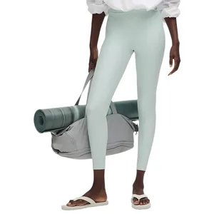 Model wearing high-waisted pastel leggings and white slide sandals, carrying a grey tote bag with a rolled-up yoga mat.