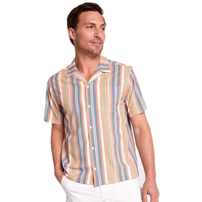 A man is wearing a short-sleeve shirt with vertical stripes in orange, blue, and white, paired with white pants.