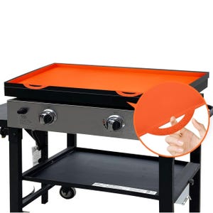 Orange silicone griddle mat designed to fit over a flat-top grill, featuring corner grips and a non-stick surface.