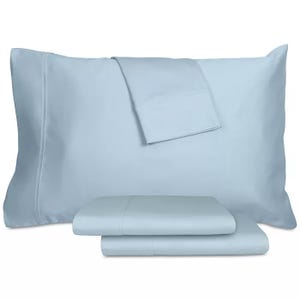 Light blue bed sheets and pillowcases neatly arranged, consisting of a flat sheet, fitted sheet, and two pillowcases.