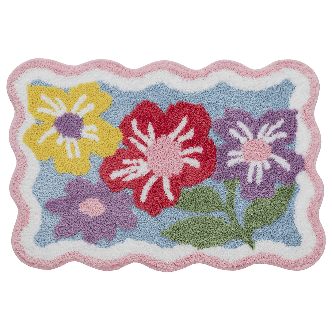 A colorful rectangular rug with a scalloped pink border, featuring a floral design with red, yellow, and purple flowers on a blue background.