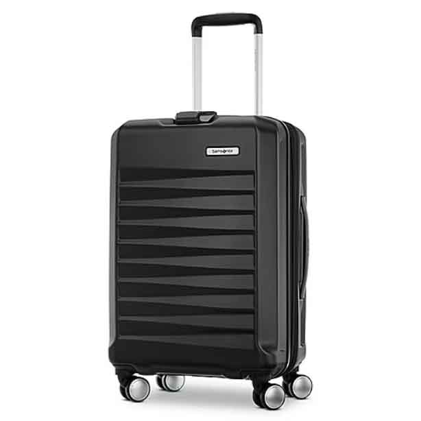 A black Samsonite Hardside Carry-On suitcase featuring a textured exterior with horizontal ridges, a retractable handle, and four multi-directional spinner wheels for easy maneuverability.
