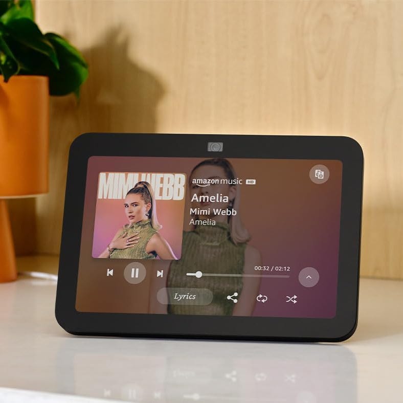 A smart display is playing music from Amazon Music, showing the interface with song details.