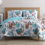 A quilt and pillow set featuring Parisian-themed designs with the Eiffel Tower, flowers, and vintage streetlights, accented with blue, red, and green colors.
