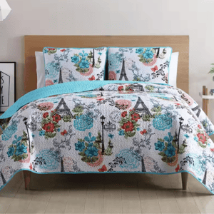 A quilt and pillow set featuring Parisian-themed designs with the Eiffel Tower, flowers, and vintage streetlights, accented with blue, red, and green colors.