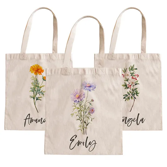 Three beige tote bags with floral designs and personalized names: Amanda, Emily, and Angela. Each bag features a different flower illustration in the center.