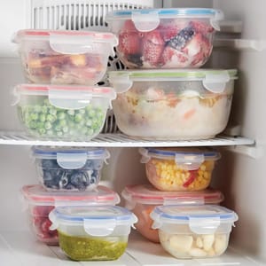 Assorted frozen foods stored in clear, airtight containers with colored lids, neatly arranged in a freezer.