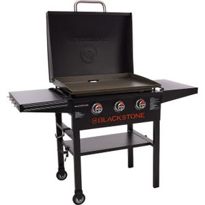 Blackstone 28\“ XL 3-Burner Griddle with side shelves, equipped with three control knobs for separate burners, features a flat top cooking surface, a storage shelf below, and is mounted on wheels for mobility.
