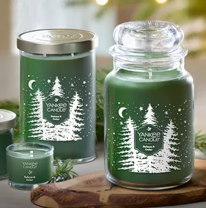 Green candles labeled \“Yankee Candle Balsam & Cedar\“ with festive tree and star designs, shown in various sizes including a jar and a votive candle.