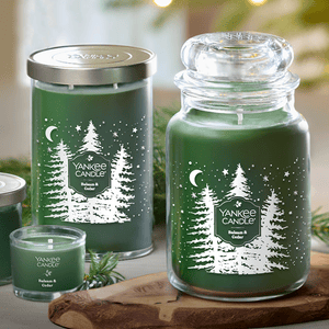 Green candles labeled \“Yankee Candle Balsam & Cedar\“ with festive tree and star designs, shown in various sizes including a jar and a votive candle.