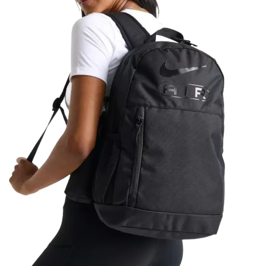 A black backpack with the Nike logo and the word \“AIR\“ is worn by a person in a white shirt.