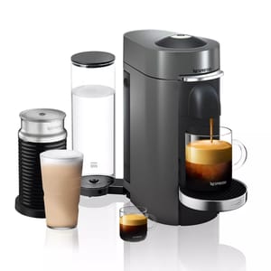 A Nespresso Vertuo coffee machine with an attached Aeroccino milk frother, a clear water tank, and two glasses filled with coffee drinks.