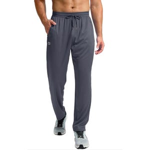 Gray men's sweatpants with an elastic waistband, adjustable drawstring, and side pockets, featuring a small logo on the left thigh. Paired with white athletic shoes.