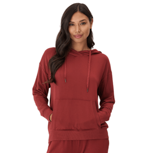 A woman is wearing a rust-colored hooded sweatshirt with drawstrings and a front pocket, paired with matching pants.