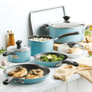 A set of light blue non-stick cookware with black handles, including frying pans with cooked chicken and broccoli, pots with lids, a large pot, and a baking sheet, arranged on a white kitchen counter.